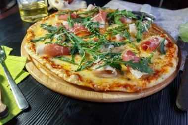 Siyah ahşap arka plan üzerinde pastırma, peynir ve otlar ile Pizza