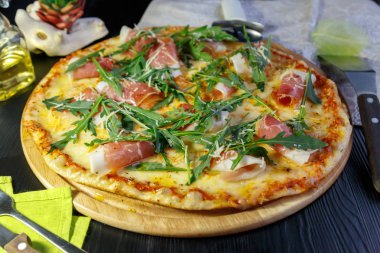 Siyah ahşap arka plan üzerinde pastırma, peynir ve otlar ile Pizza