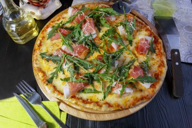 Siyah ahşap arka plan üzerinde pastırma, peynir ve otlar ile Pizza