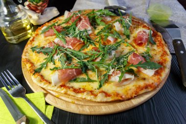 Siyah ahşap arka plan üzerinde pastırma, peynir ve otlar ile Pizza