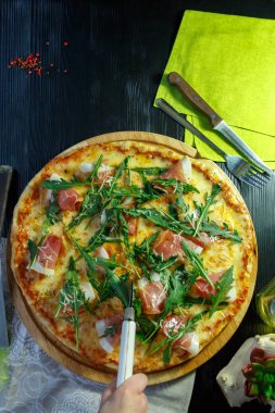 Siyah ahşap arka plan üzerinde pastırma, peynir ve otlar ile Pizza