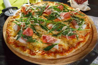 Siyah ahşap arka plan üzerinde pastırma, peynir ve otlar ile Pizza