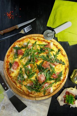 Siyah ahşap arka plan üzerinde pastırma, peynir ve otlar ile Pizza