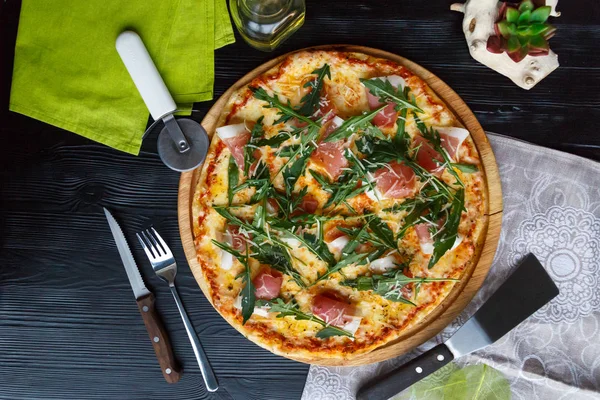 Siyah ahşap arka plan üzerinde pastırma, peynir ve otlar ile Pizza