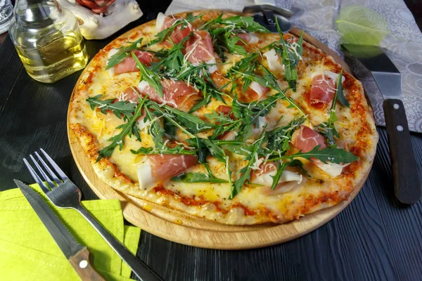Siyah ahşap arka plan üzerinde ahşap bir çanak üzerinde pastırma, peynir ve otlar ile Pizza