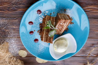 Dondurma topu ve ahşap bir arka plan üzerinde mavi bir tabak üzerinde kek parçaları