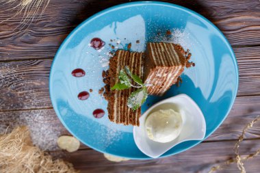 Dondurma topu ve ahşap bir arka plan üzerinde mavi bir tabak üzerinde kek parçaları