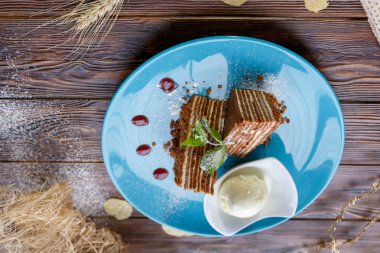 Dondurma topu ve ahşap bir arka plan üzerinde mavi bir tabak üzerinde kek parçaları