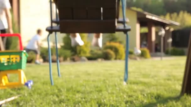 El niño está montando en un columpio en el patio de recreo — Vídeo de stock