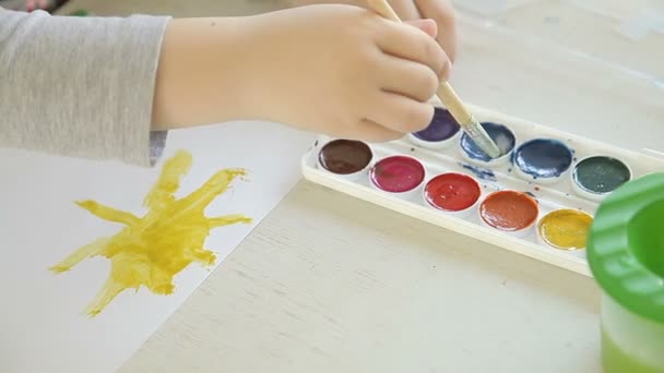 De jongen een penseel tekent en schildert de zon — Stockvideo