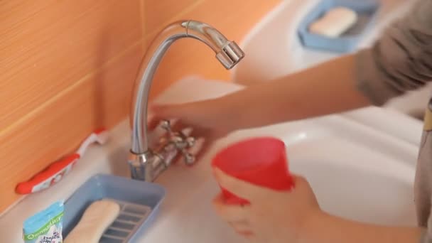 Ребенок наливает воду в стакан — стоковое видео