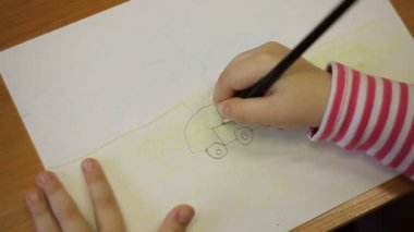 Bir çocuk bir araba bir kalemle çizer.