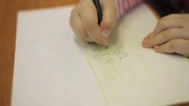 Bir çocuk bir kalem bir resimle bir daktilo ile çizer.