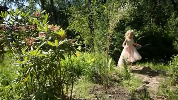 Lilla flickan promenerar i blomsterträdgården — Stockvideo