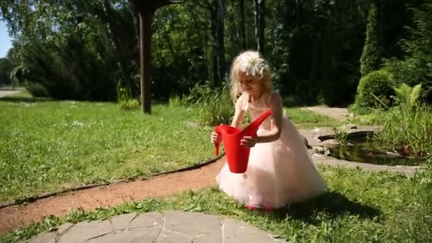 Niña toma una regadera roja — Vídeo de stock