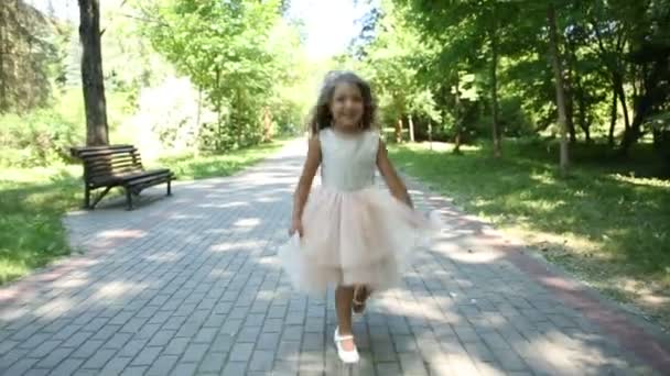 Little girl in dress runs and jumps in summer park — Stock Video