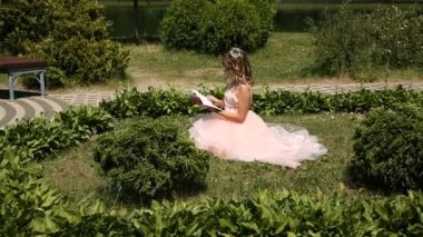 Genç bir kız parkta çim üzerine bir kitap okur