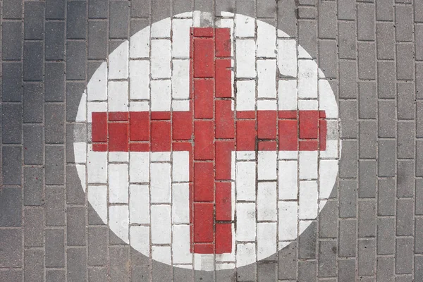Sign of the medical red cross on the sidewalk
