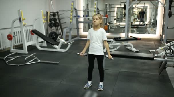 Klein meisje in de sportschool bezig met halters — Stockvideo