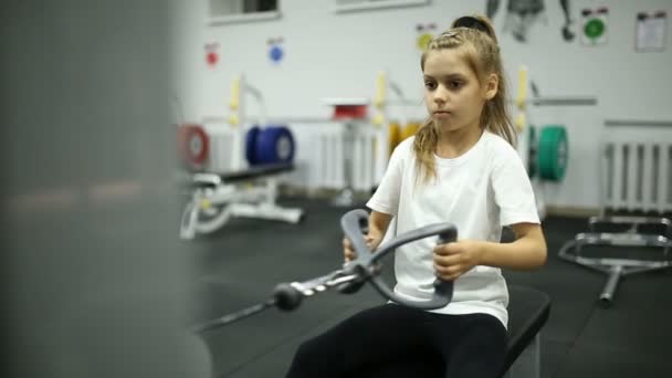 A little girl in the gym is exercising on the machine — Stock Video