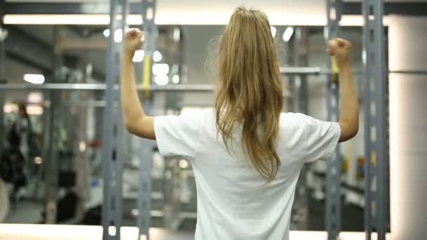 Meisje kijkt naar haar spieren in de spiegel — Stockvideo