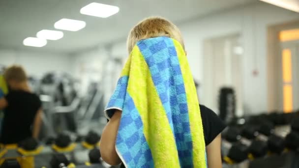 De jongen in de sportschool is zweten met een handdoek — Stockvideo