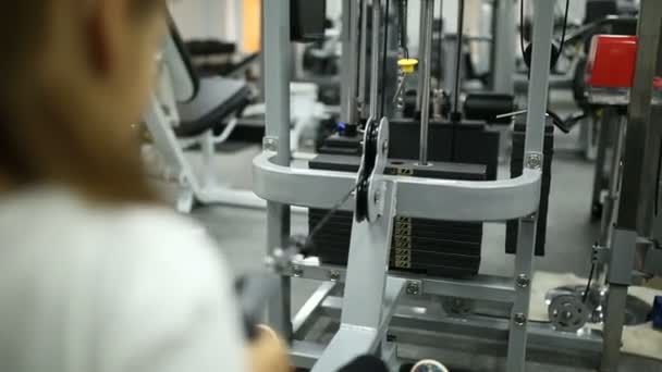 A little girl in the gym is exercising on the simulator — Stock Video