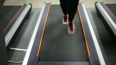 Fitness salonunda bir koşu bandı üzerinde çalışan kız