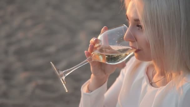 Una chica está bebiendo vino en la playa — Vídeos de Stock