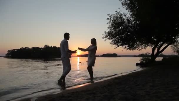 Los amantes se besan al atardecer junto al agua — Vídeos de Stock