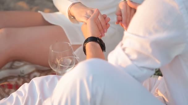 Любящая пара, держащаяся за руки, сидя на пляже — стоковое видео