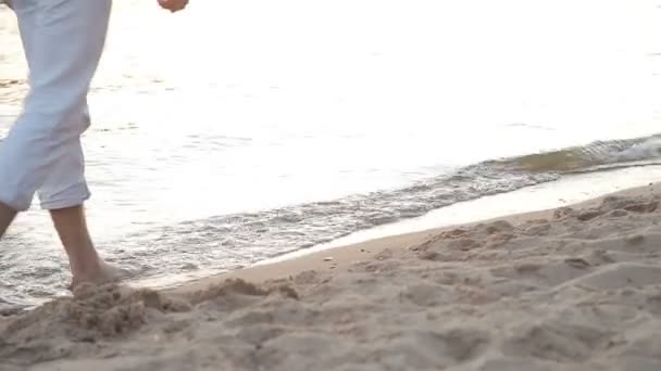 El chico y la chica van descalzos en la playa — Vídeos de Stock