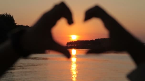 Символ любви, сердце из рук влюбленных на закате — стоковое видео