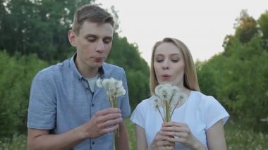 Adam ve kız dandelions üfleme vardır