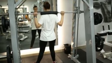 Spor salonunda güzel kız bir halter ile crouches