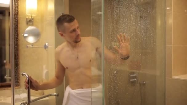 Un giovane esce dalla doccia in un asciugamano — Video Stock