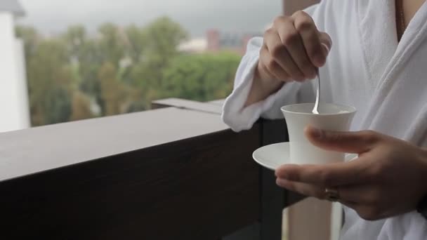 Un hombre con un albornoz está revolviendo café con una cuchara — Vídeos de Stock