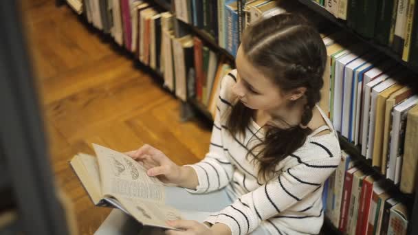 Meisje zittend op de vloer en het bladeren door een boek — Stockvideo