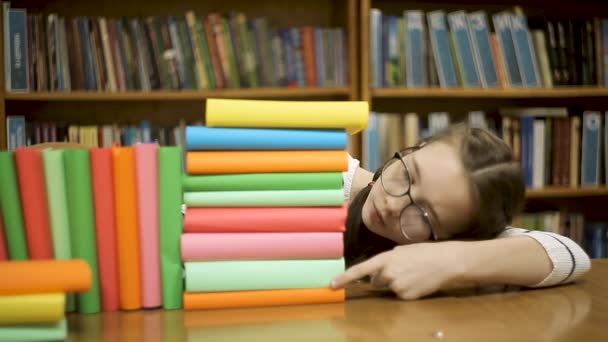 Uma menina com óculos conta quantos livros — Vídeo de Stock