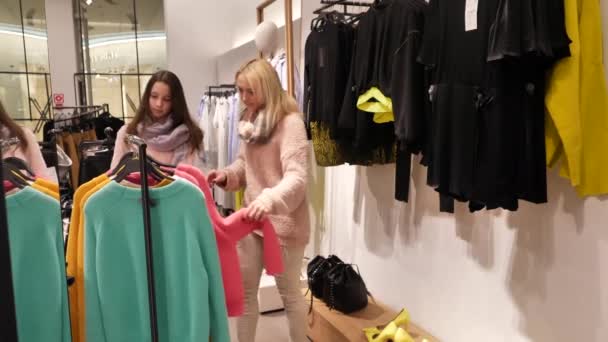 Vrouw en dochter Kies kleding in het winkelcentrum — Stockvideo