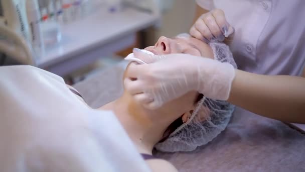 美容師の手は、水の剥離を行い、患者の顔を掃除します. — ストック動画