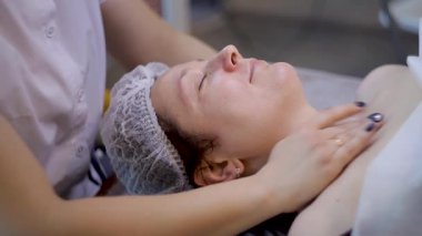 Güzel genç kadın rahatlatıcı kadın yüz masajı, güzellik spa alan.