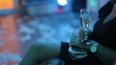 Bir gece kulübünde elinde beyaz şarap bir bardak ile elbiseli bir kadın.