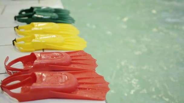 Aletas de buceo en tres colores diferentes en el borde de la piscina . — Vídeos de Stock