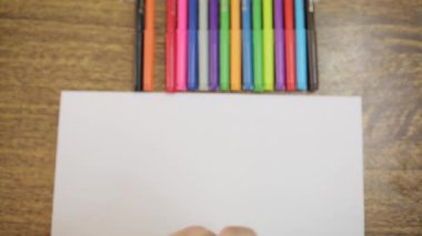 Çocuk beyaz bir kağıt üzerinde sarı keçeli kalem ile çizer. Yakın çekim çizmek için keçeli kalem ile Childs el. Çocuk sarı bir güneş çizer..