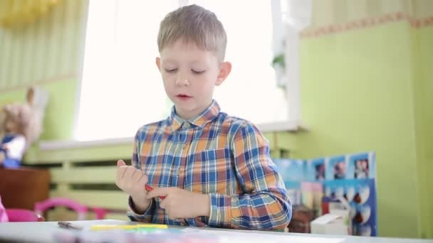 Chłopiec w koszuli czerpie z żółtego pióra z końcówką. Uczeń wykonuje zadanie w przedszkolu. — Wideo stockowe