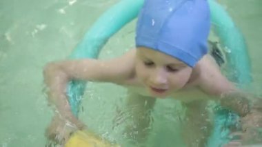 Havuzdaki lastik yüzüklü çocuk. Küçük kız havuzda lastik bir halkada yüzüyor..