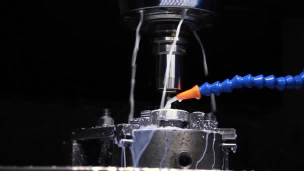 The machine grinds a part from metal. Cooling fluid is pouring — ストック動画
