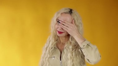 Kıvırcık sarı saçlı, güzel ve hevesli bir kadının portresi gözlerini kapar ve parmaklarından gülümseyerek bakar. İyimser bir bakışla geleceğe bakıyorum.