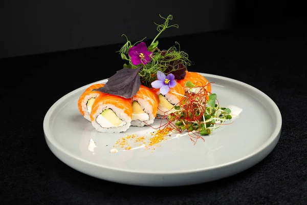 Avokadoyla süslenmiş suşi Philadelphia usulü. Tabakta otlar, klasik Japon suşisi. Geleneksel Japon yemeği ve maki. Lezzetli suşi parçaları. Restoran menüsü için. kopyalama alanı